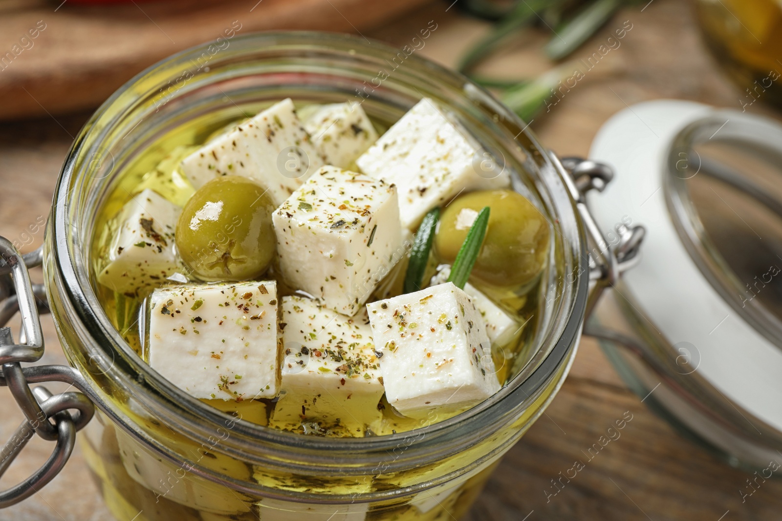 Photo of Pickled feta cheese in jar on wooden table, closeup