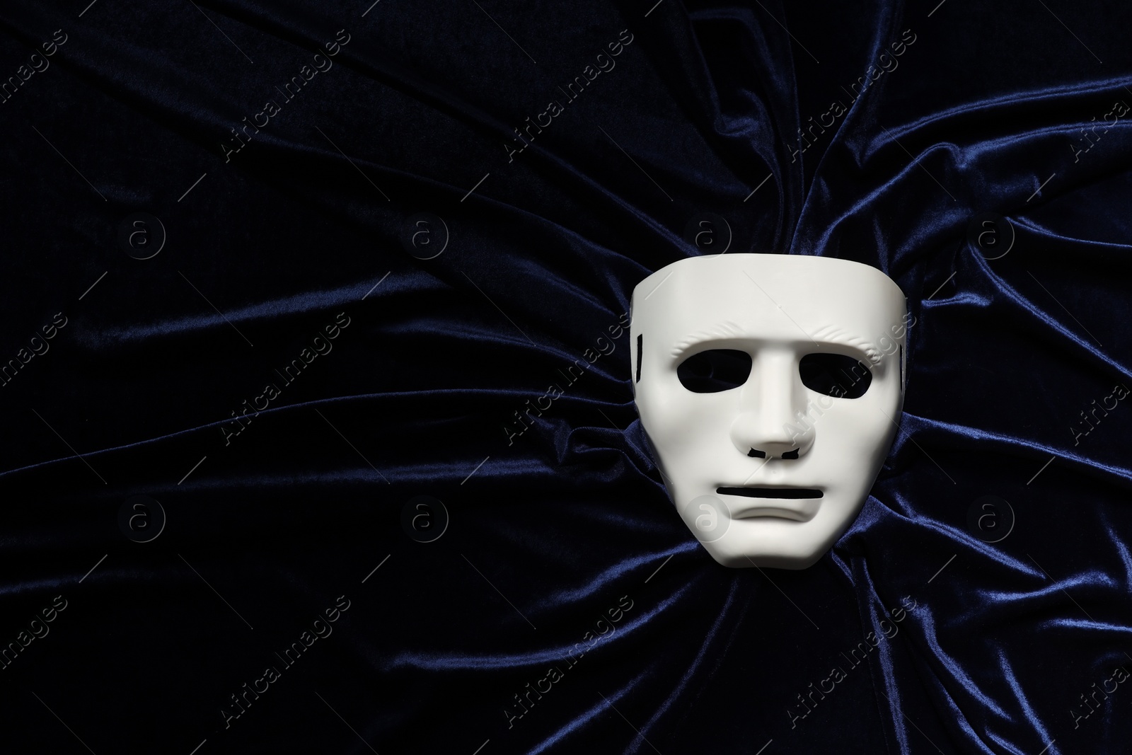 Photo of Theater arts. White mask on blue fabric, top view. Space for text