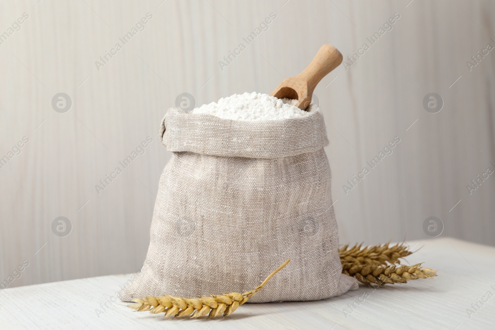 Photo of Wheat flour and spikelets on white table