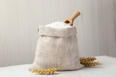 Photo of Wheat flour and spikelets on white table