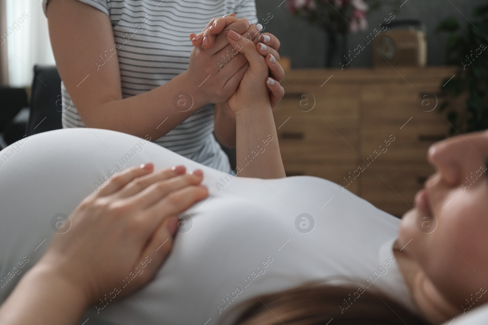 Photo of Doula taking care of pregnant woman indoors, closeup. Preparation for child birth