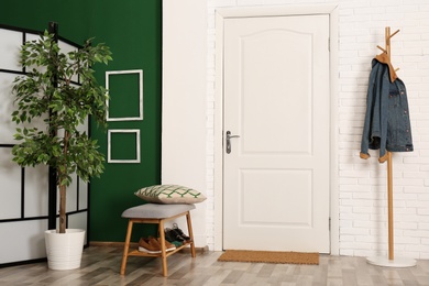 Stylish hallway interior with shoe storage bench and hanger stand