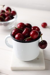 Fresh ripe cherries with water drops on white wooden table