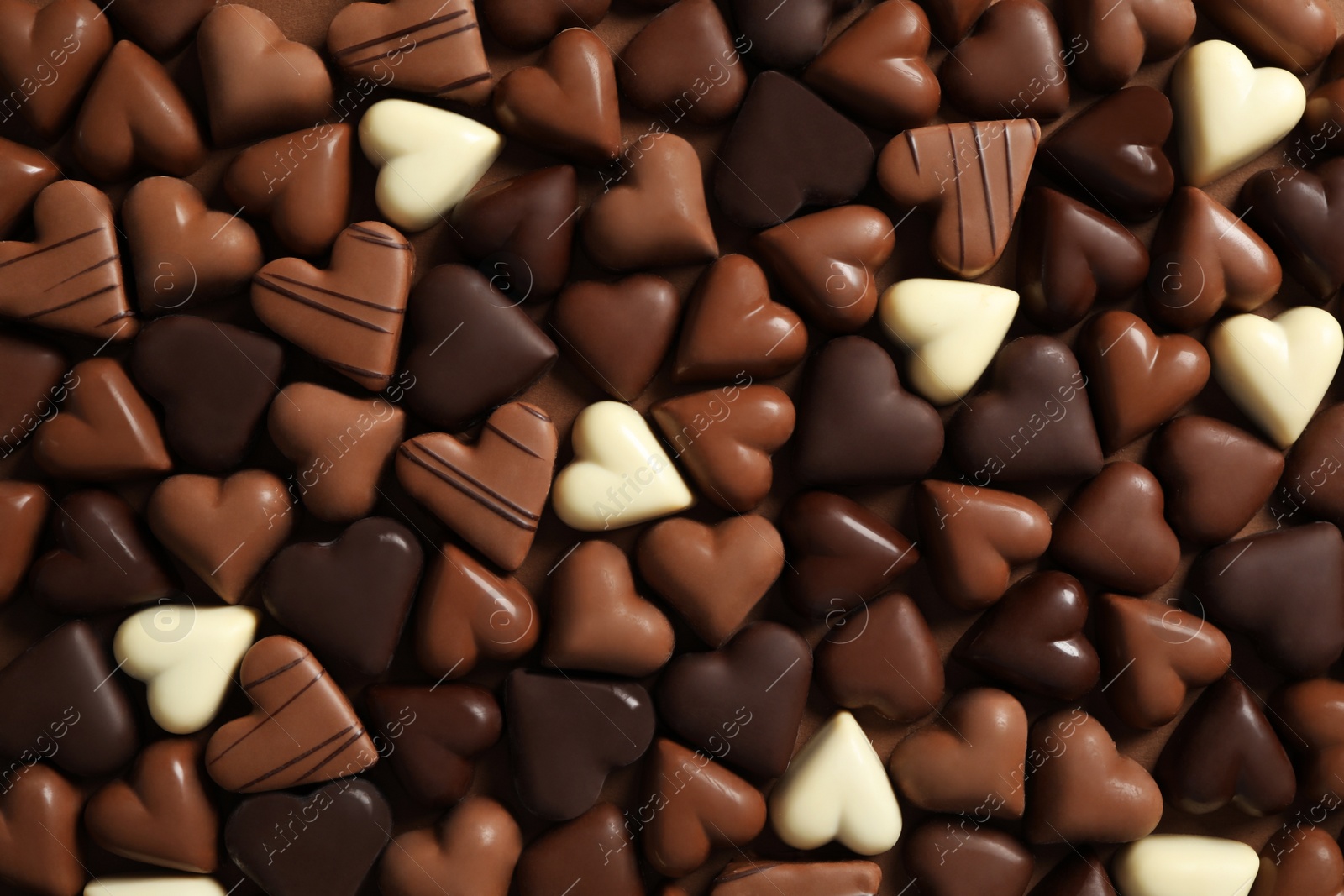 Photo of Beautiful heart shaped chocolate candies on brown background, flat lay