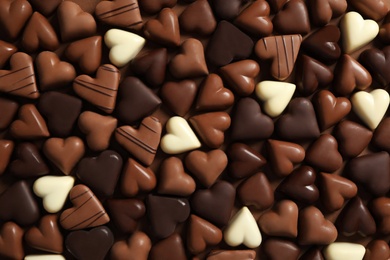 Beautiful heart shaped chocolate candies on brown background, flat lay