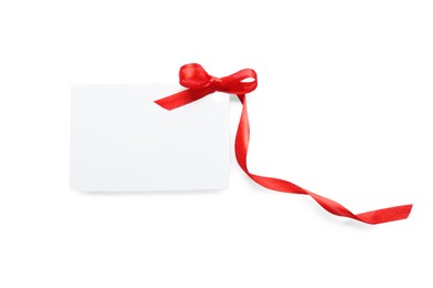Photo of Blank gift tag with red satin ribbon on white background, top view