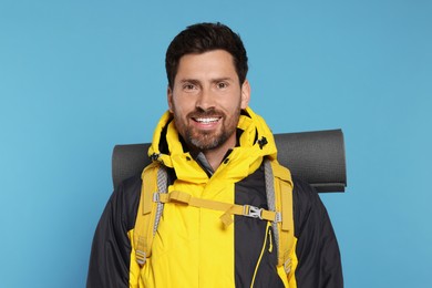 Photo of Happy tourist with backpack on light blue background