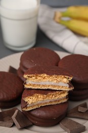 Photo of Tasty banana choco pies and pieces of chocolate on plate, closeup. Space for text