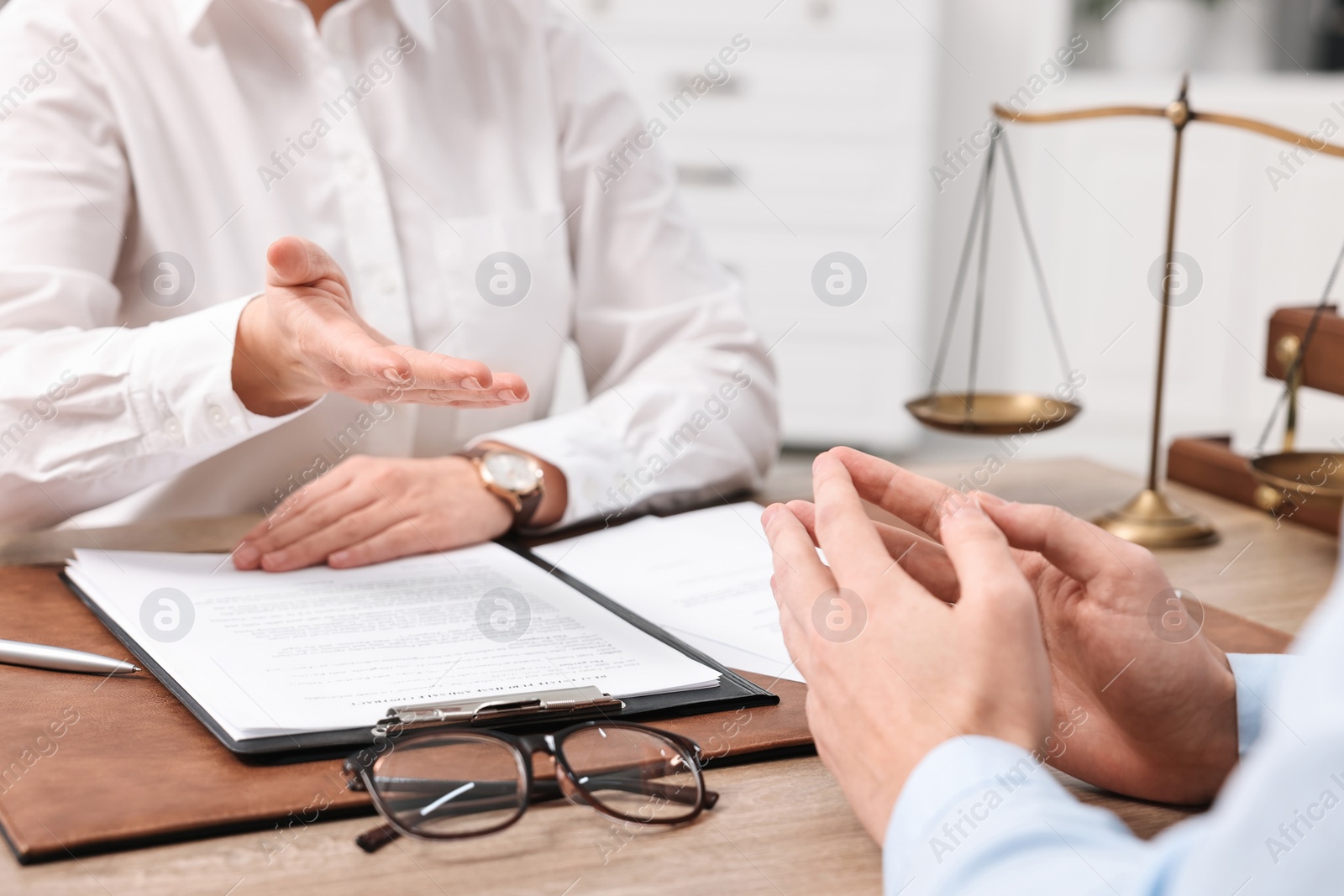Photo of Lawyers working with documents at wooden table in office, closeup