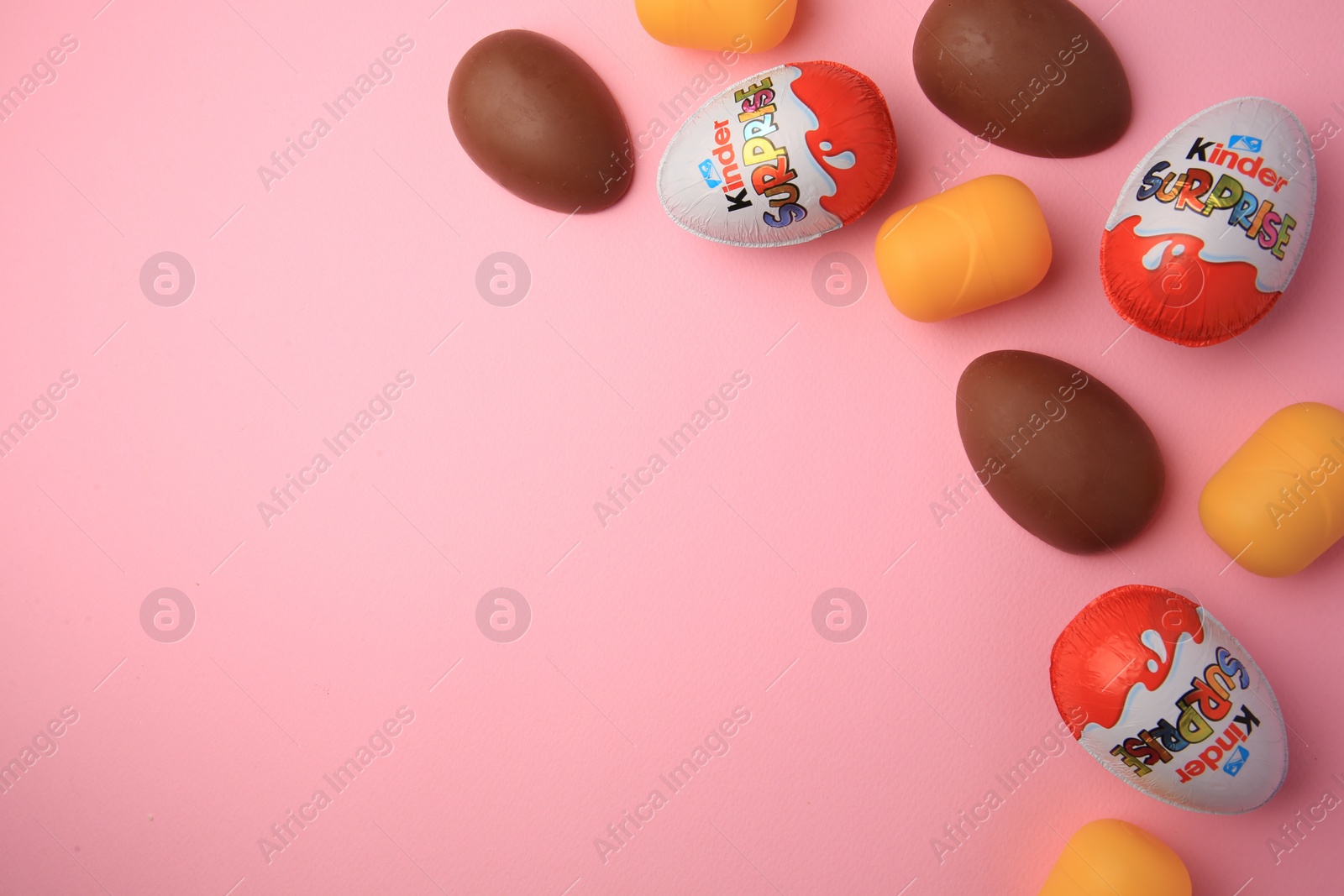 Photo of Sveti Vlas, Bulgaria - June 30, 2023: Kinder Surprise Eggs and plastic capsules on pink background, flat lay. Space for text