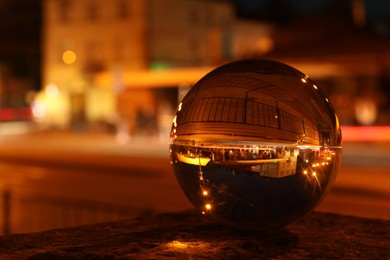 Photo of Beautiful city street, overturned reflection. Crystal ball at night, closeup. Space for text