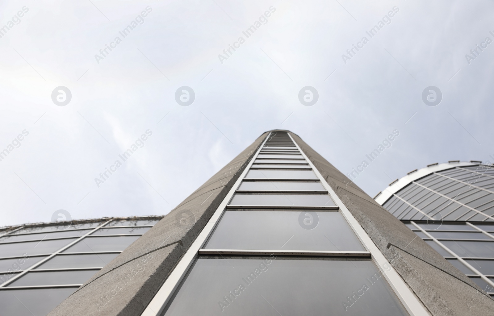 Photo of Modern building with tinted windows against sky, low angle view. Urban architecture