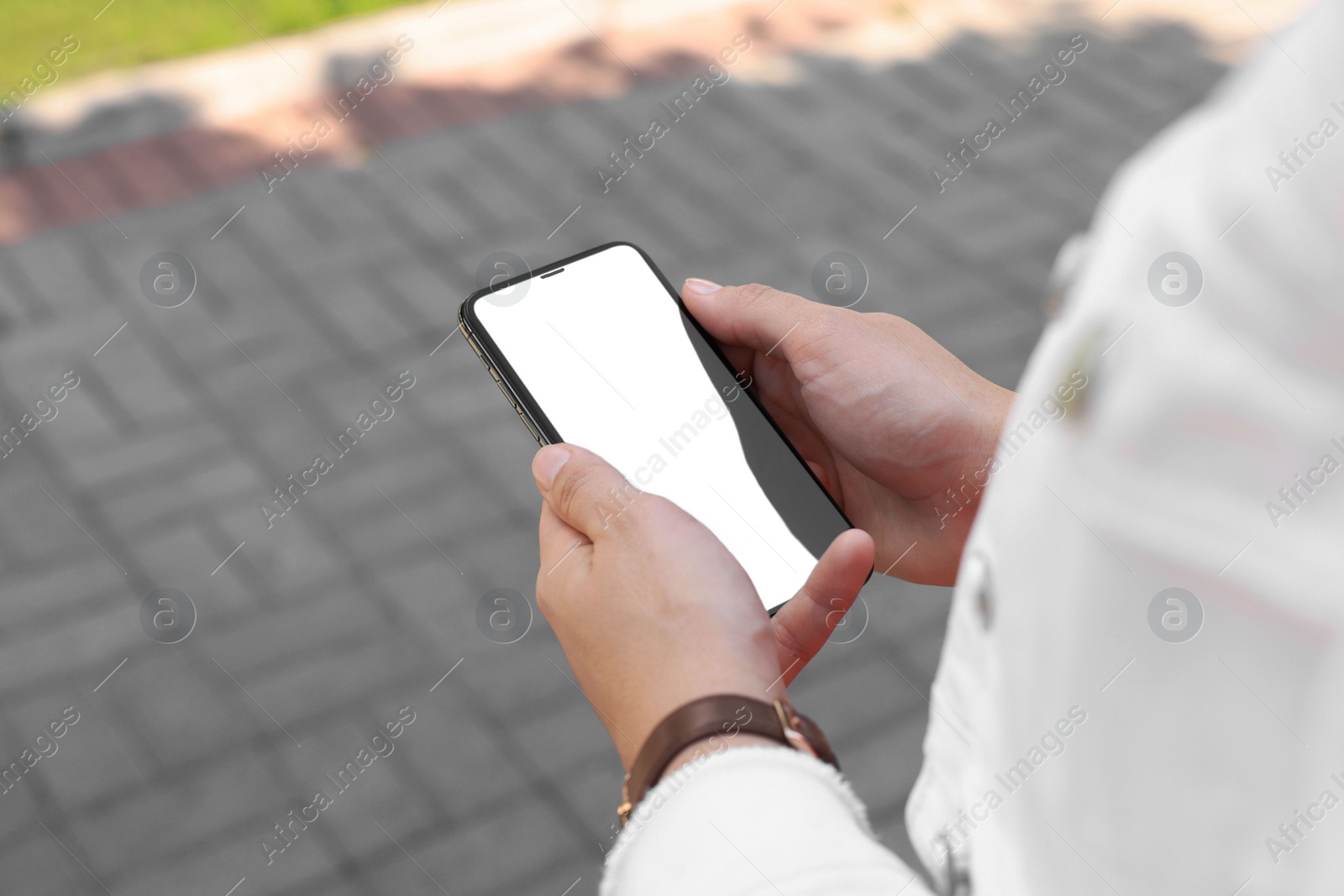Photo of Woman with smartphone on pavement outdoors, closeup view