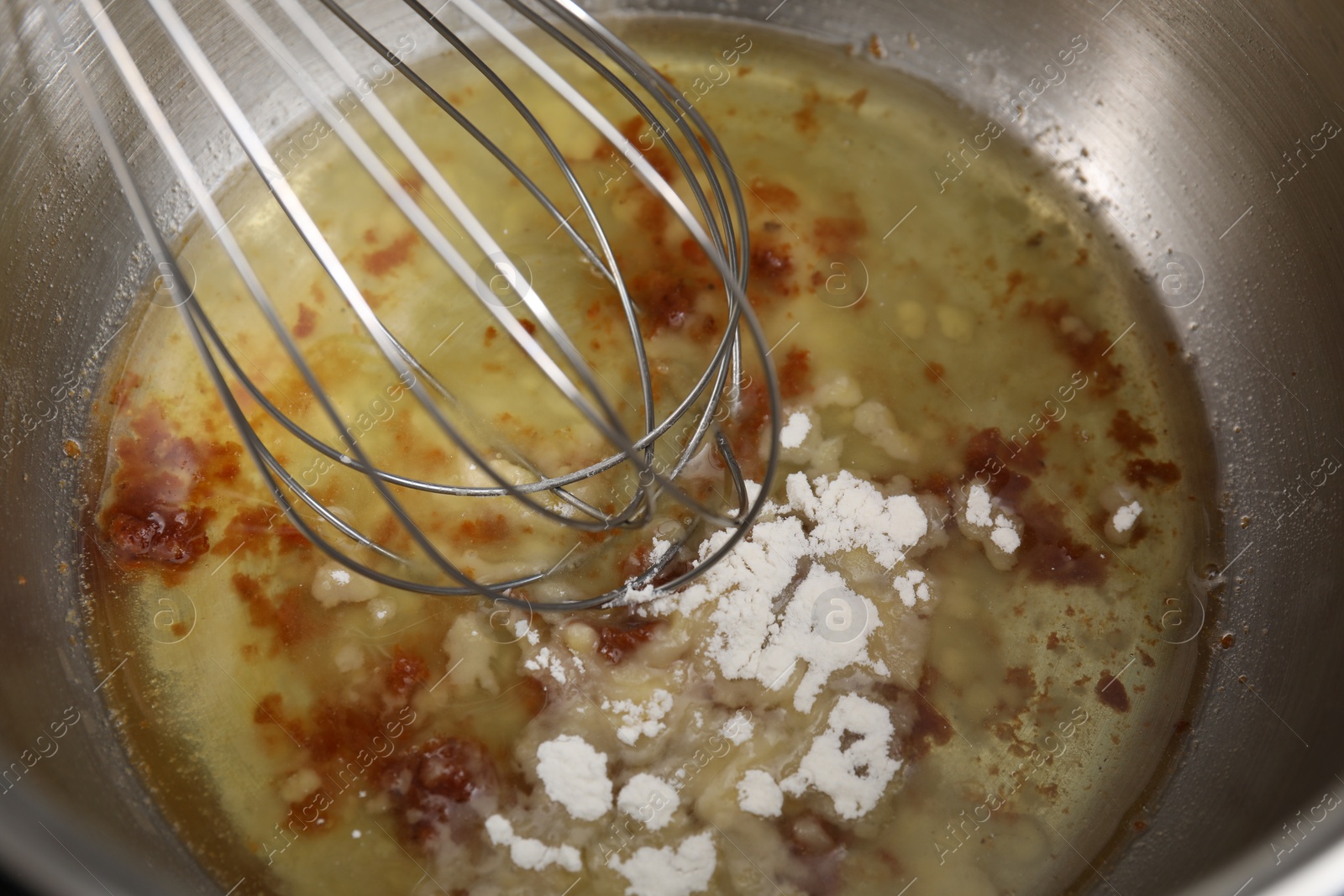 Photo of Cooking delicious turkey gravy. Mixing ingredients with whisk in pot, closeup