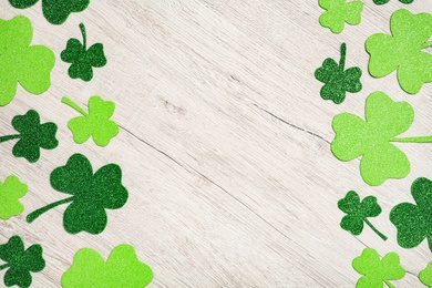 Photo of Decorative clover leaves on white wooden table, flat lay with space for text. Saint Patrick's Day celebration