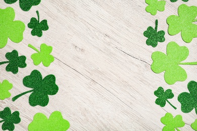 Decorative clover leaves on white wooden table, flat lay with space for text. Saint Patrick's Day celebration