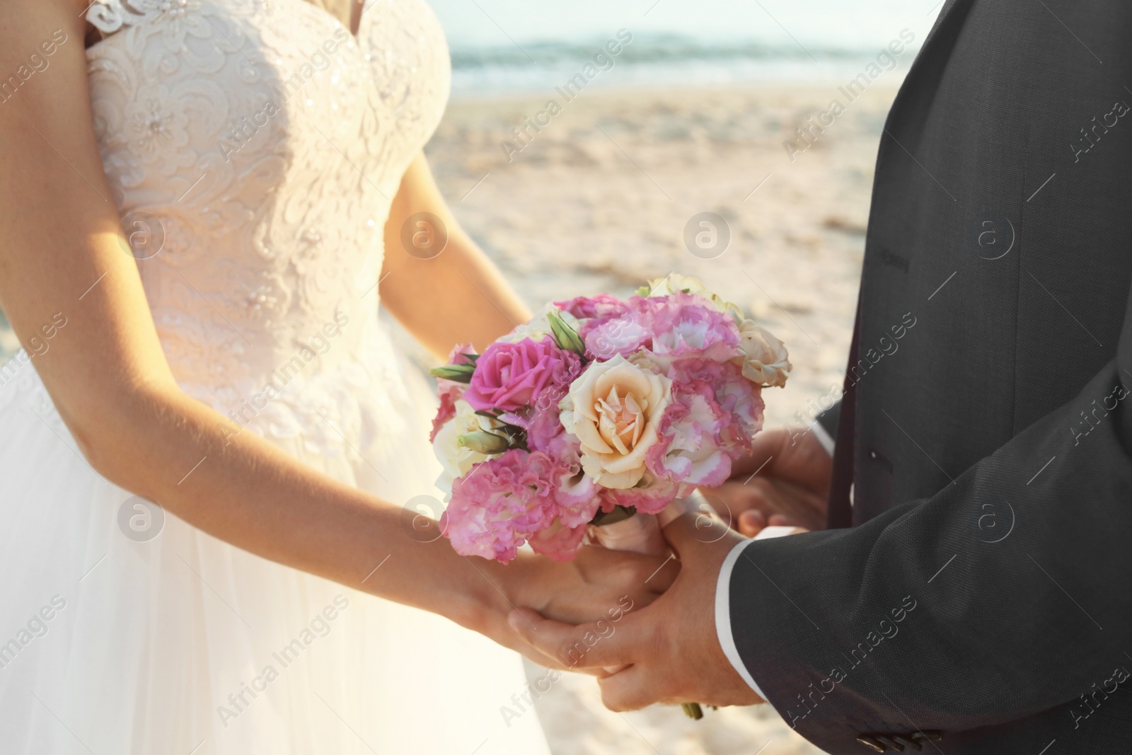 Photo of Close up view of wedding couple holding bouquet on beach