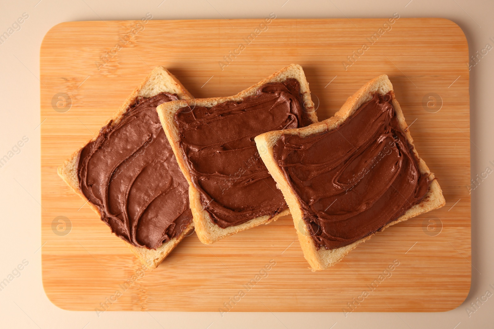 Photo of Tasty toasts with chocolate paste on beige background, top view