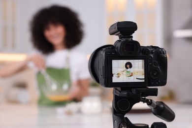 Photo of Food blogger recording video in kitchen, focus on camera