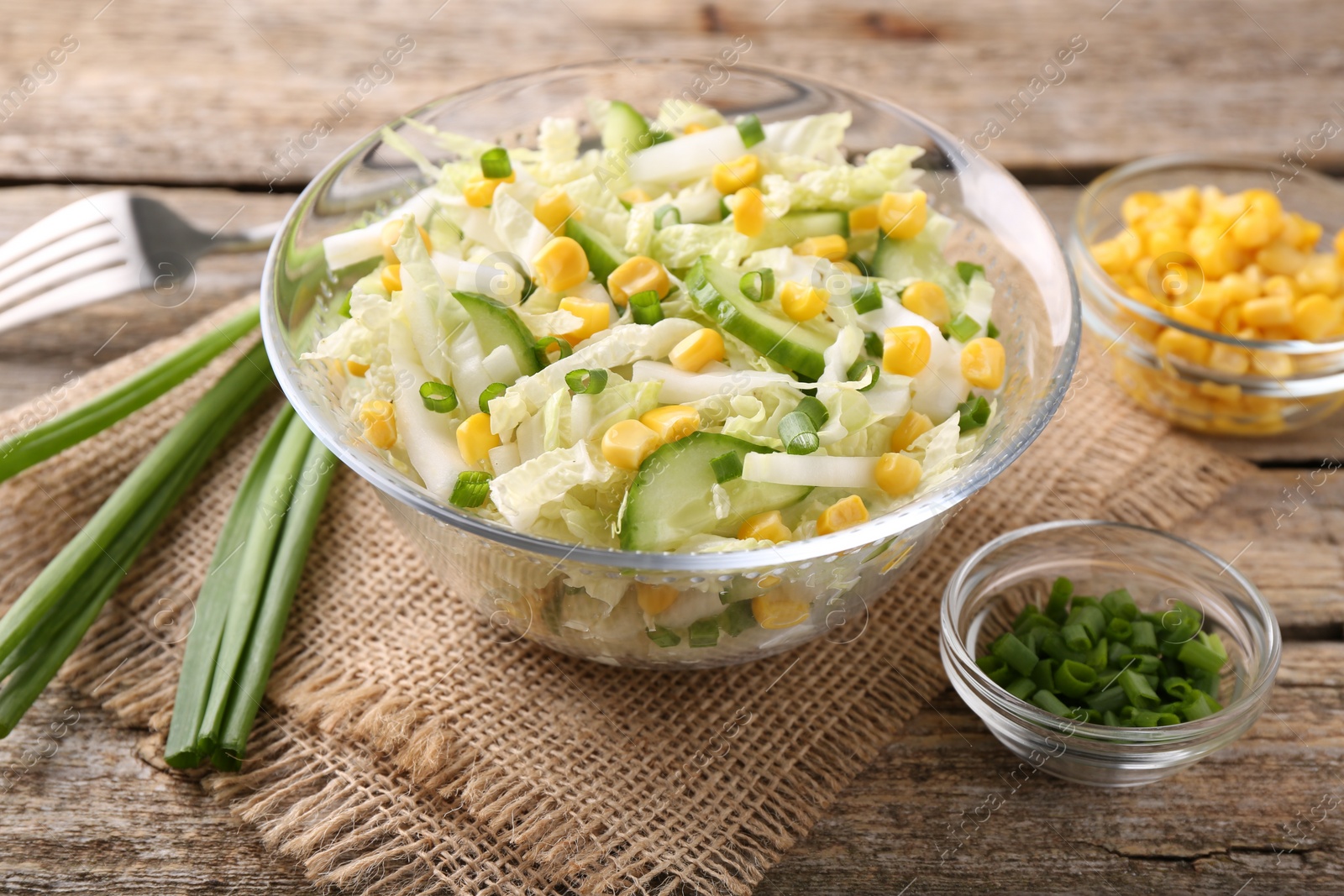 Photo of Tasty salad with Chinese cabbage, corn and green onion on wooden table