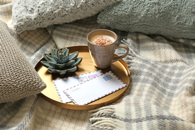 Photo of Pillows, plaid, tray with cup of coffee and letters on bed