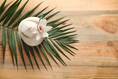 Composition with fresh coconut drink in nut on wooden background