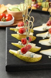 Photo of Tasty canapes with pears, blue cheese and prosciutto on grey table, closeup