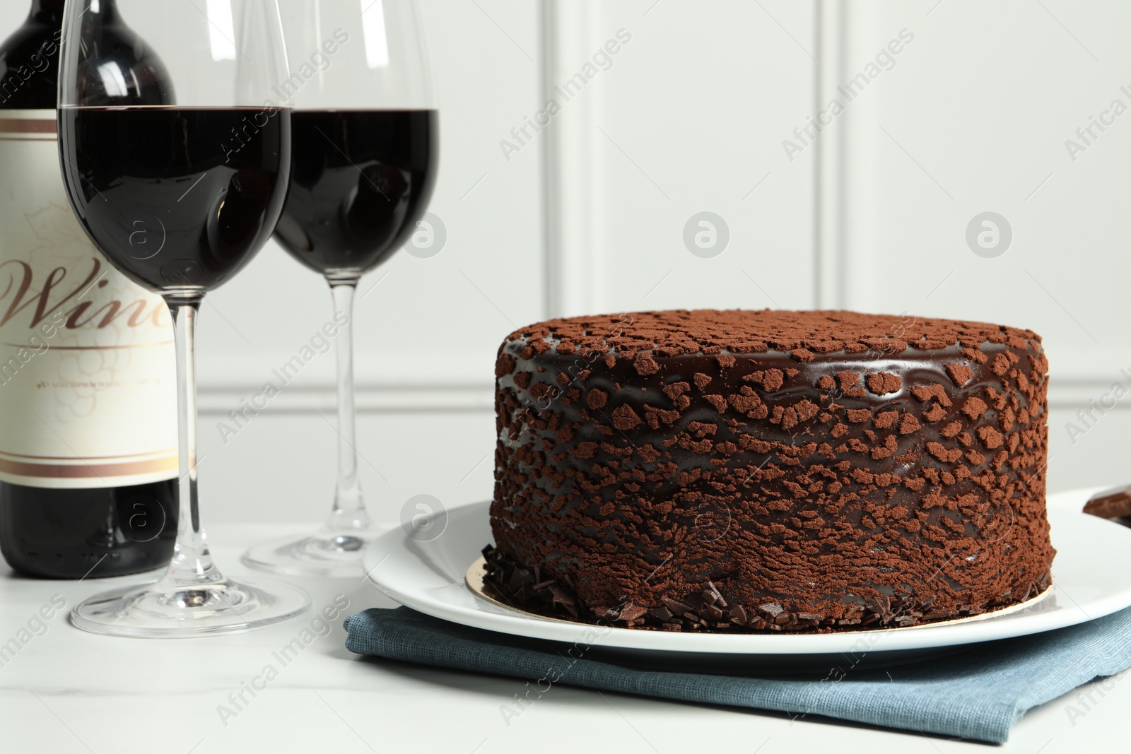 Photo of Delicious chocolate truffle cake and red wine on white marble table