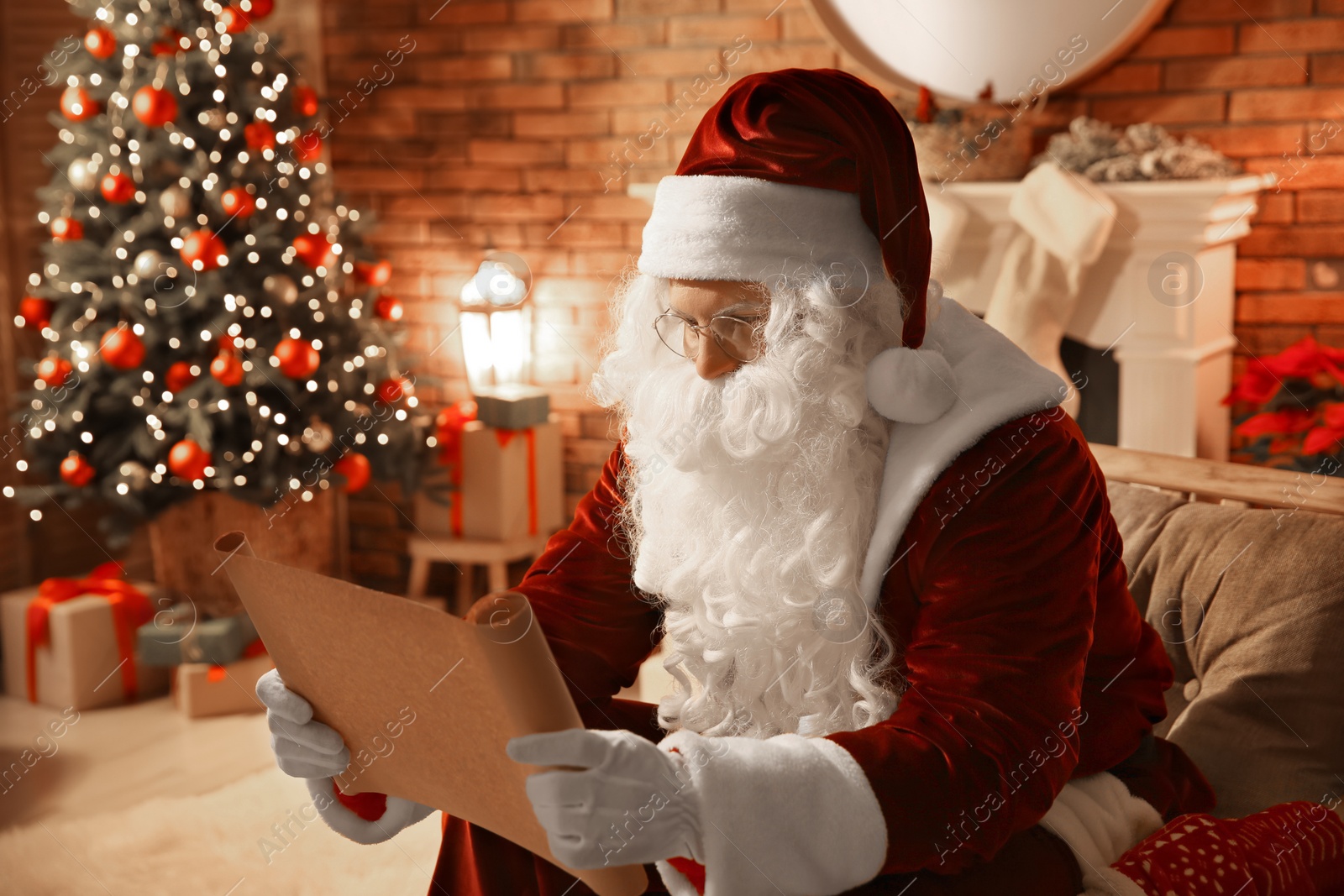 Photo of Santa Claus in glasses reading wish list indoors