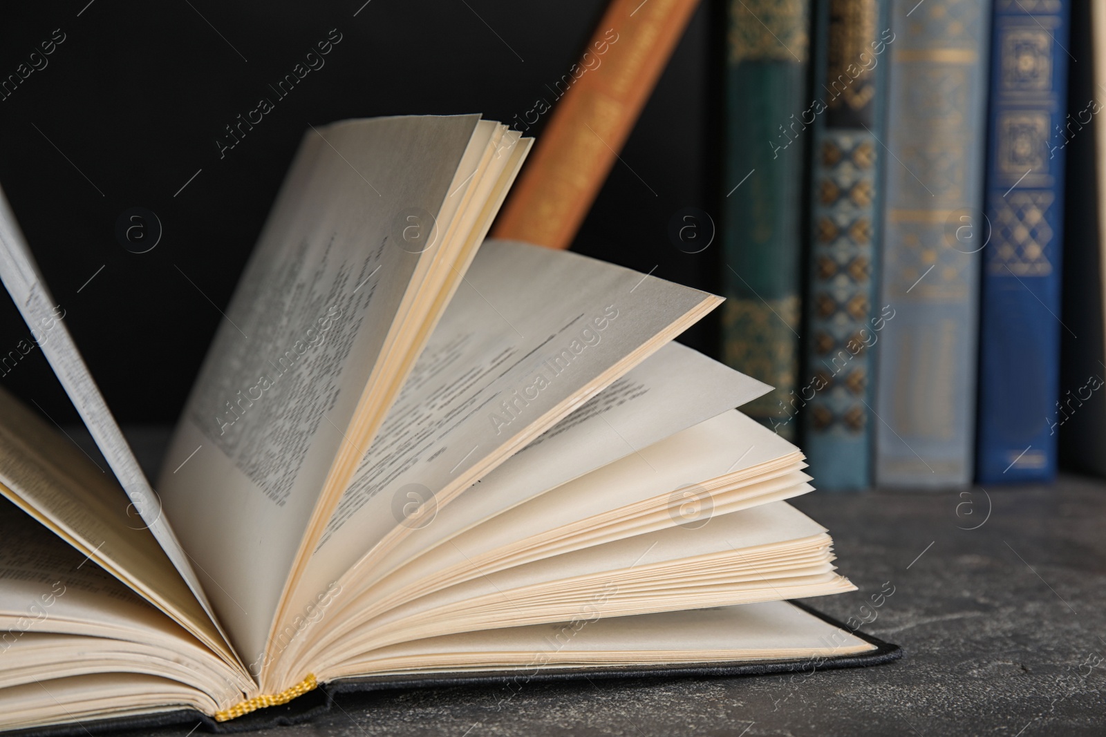 Photo of Open hardcover book on grey stone table, closeup