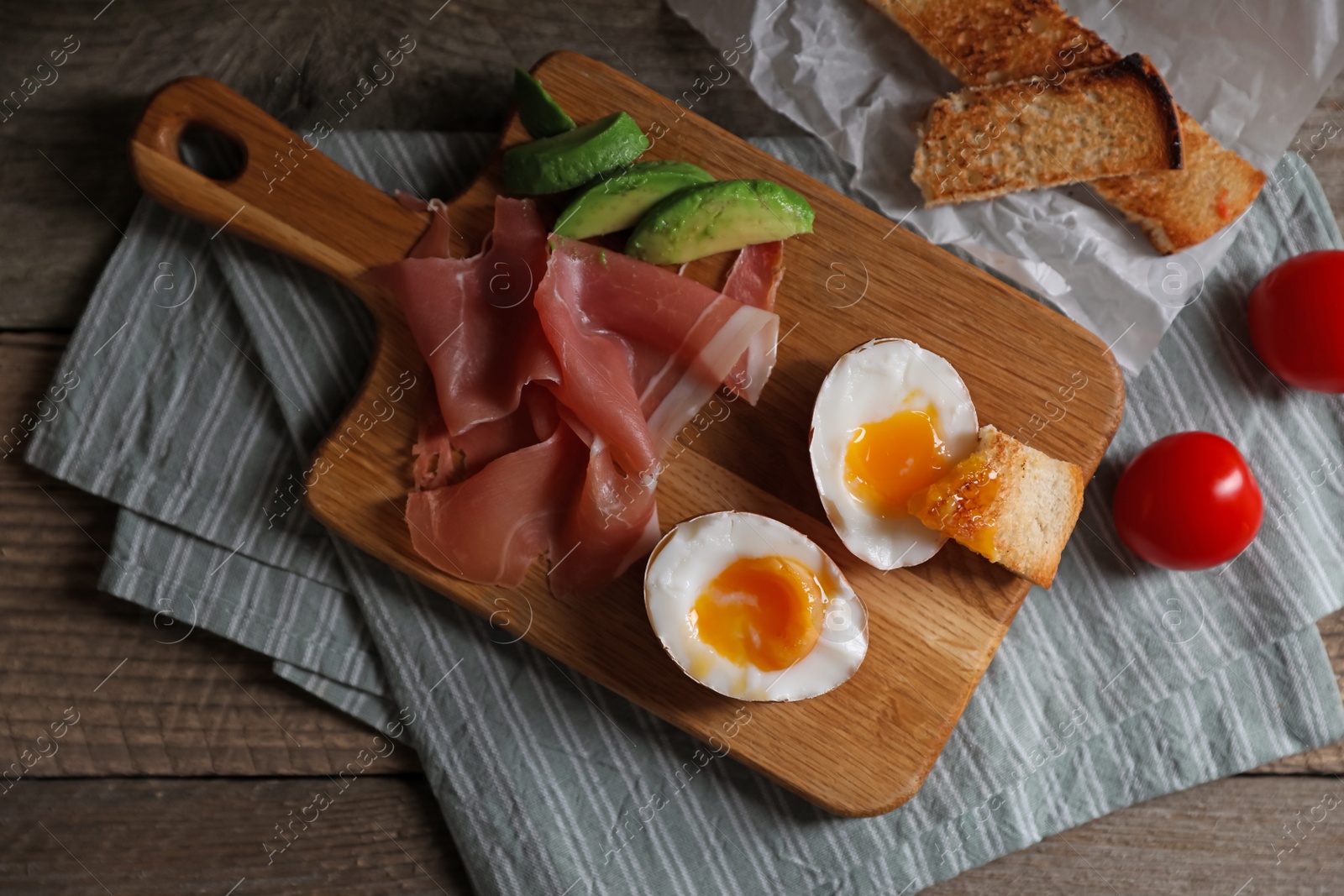 Photo of Delicious breakfast with soft boiled egg and tasty prosciutto served on wooden table, flat lay