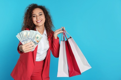 African-American businesswoman with money and shopping bags on color background. Space for text