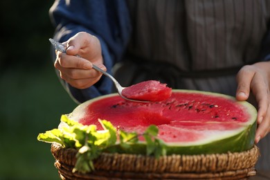 Woman holding spoon of delicious ripe watermelon outdoors, closeup
