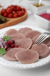 Photo of Tasty beef tongue pieces, berries and red onion on white table, closeup