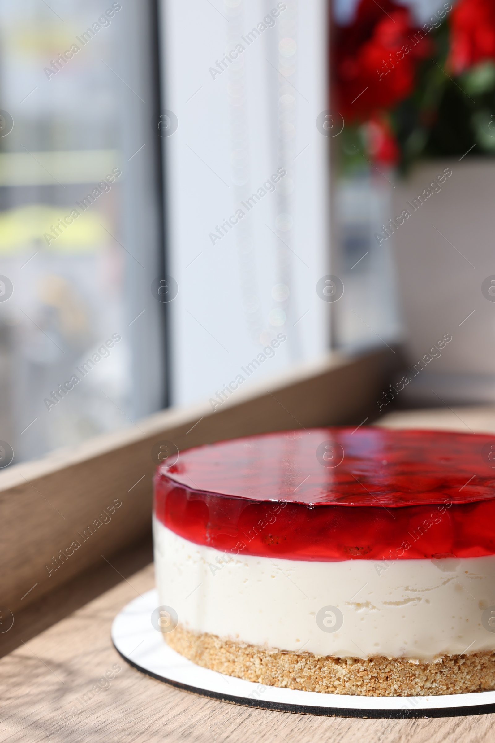 Photo of Delicious cheesecake with jelly and strawberries on wooden table. Space for text