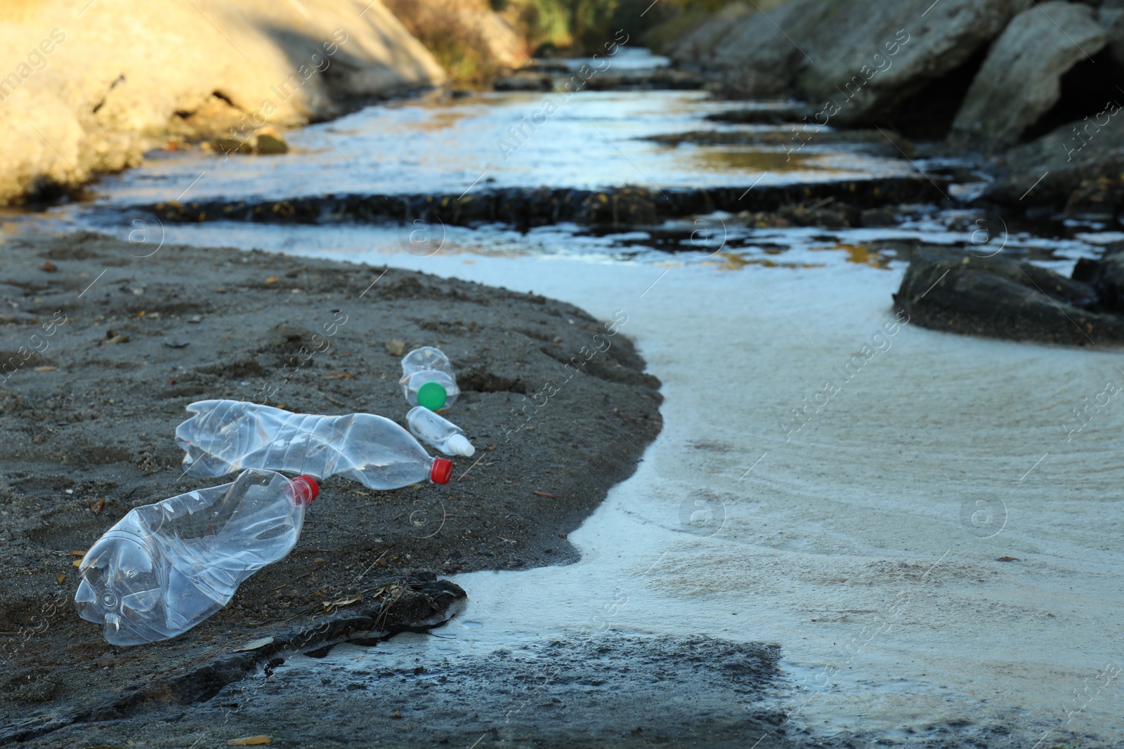 Photo of Used plastic bottles near water at beach, space for text. Environment pollution