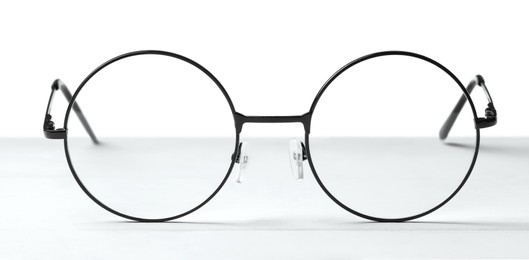 Round glasses with metal frame on table against white background