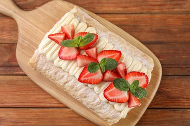 Delicious cake roll with strawberries and cream on wooden table, top view