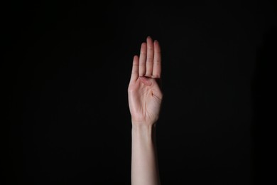 Photo of Woman showing open palm on black background, closeup