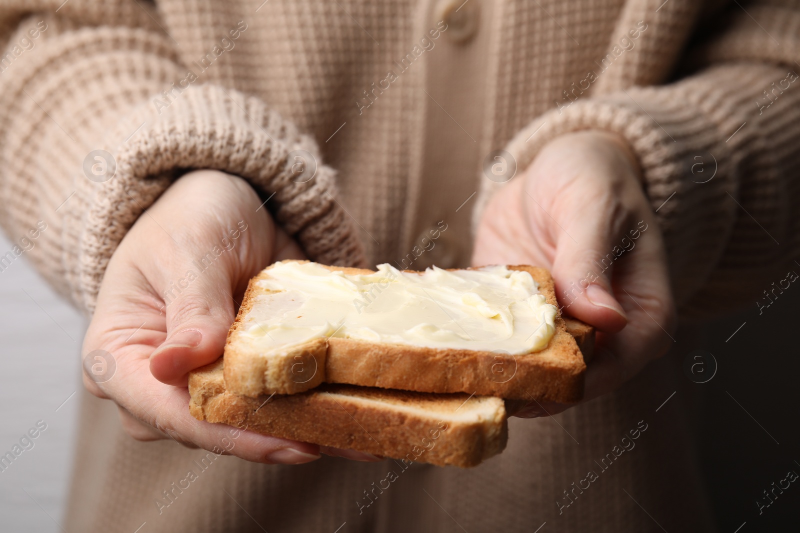 Photo of Woman holding toasts with butter, closeup view