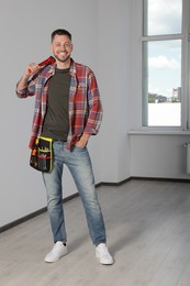 Handsome worker with wrench in empty room