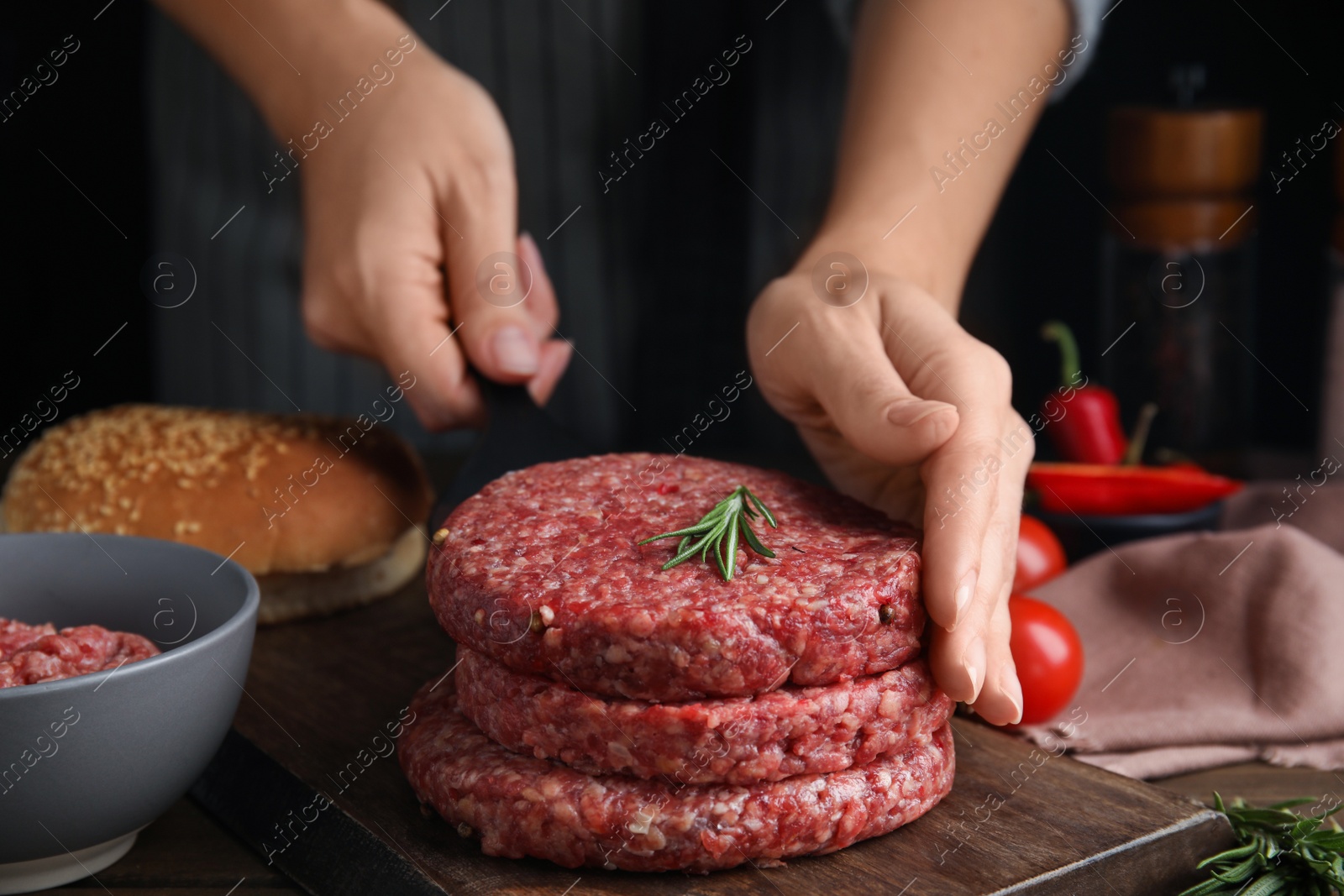 Photo of Woman making raw hamburger patty at wooden table, closeup