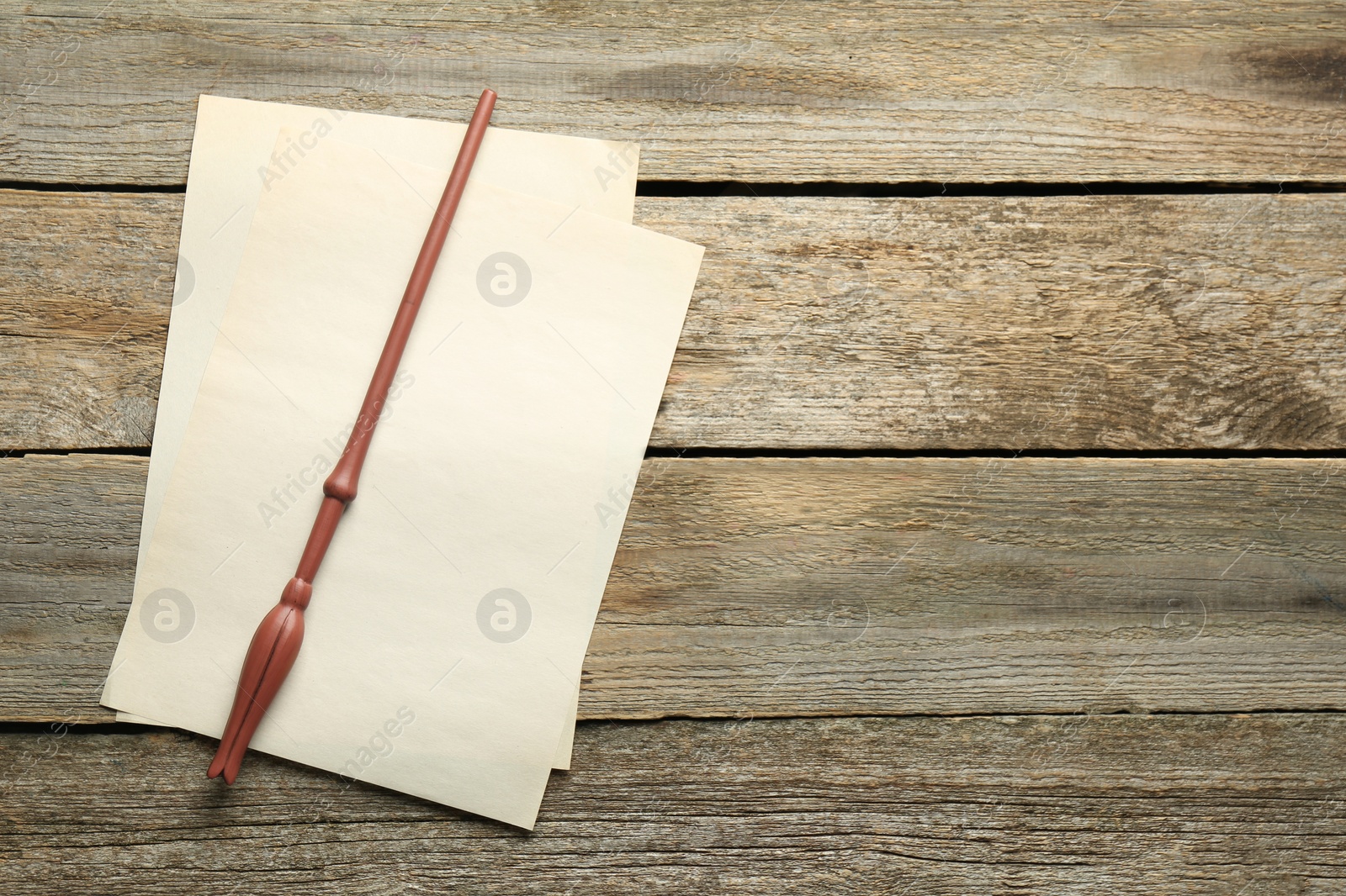 Photo of Old magic wand and sheets of paper on wooden table, top view. Space for text