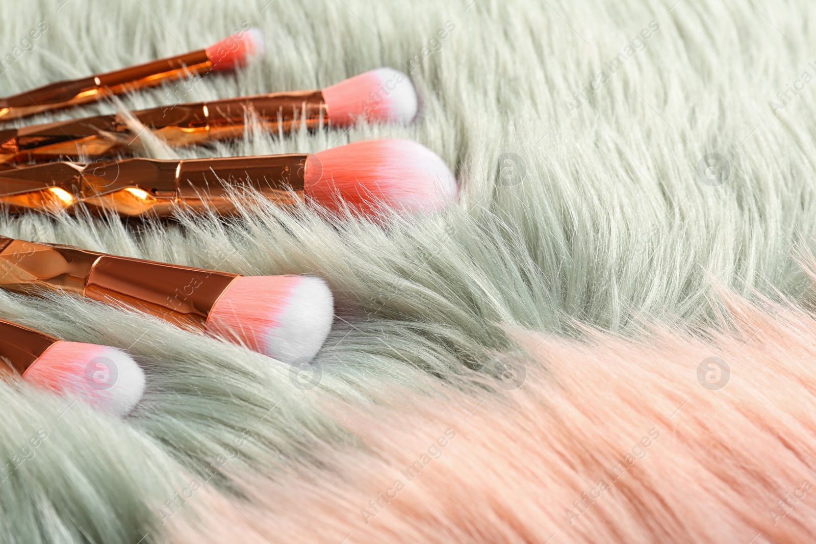 Photo of Set of professional makeup brushes on furry fabric. Space for text