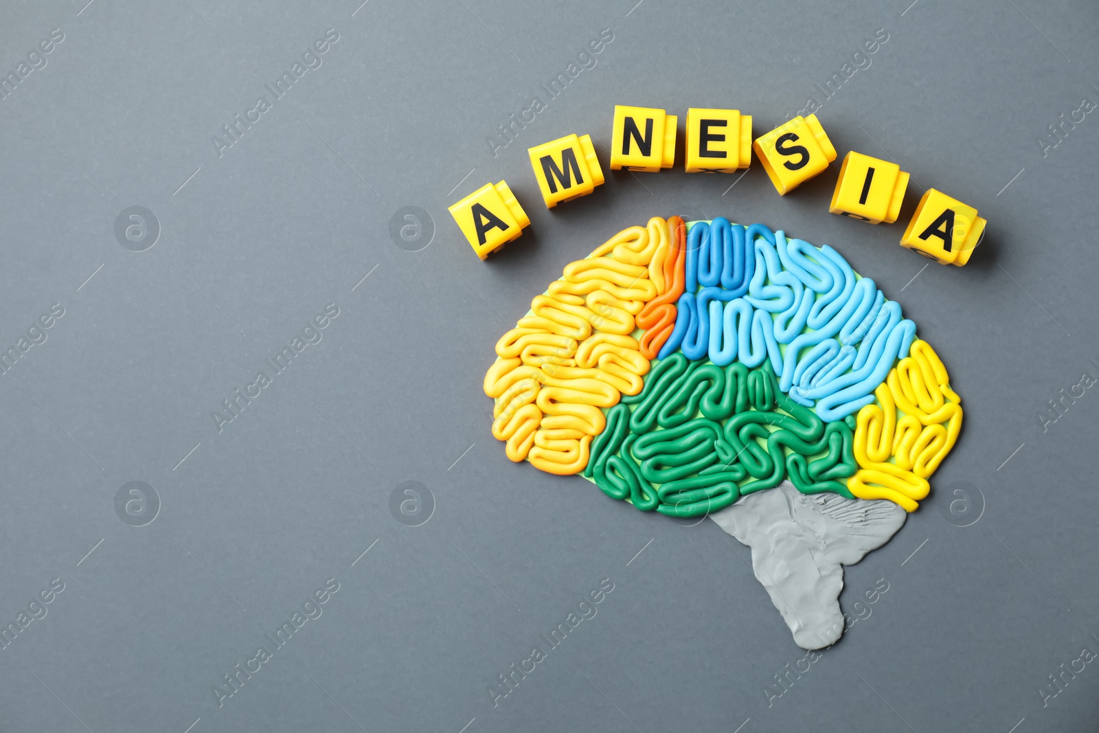 Photo of Word Amnesia and brain with sections made of plasticine on grey background, flat lay. Space for text