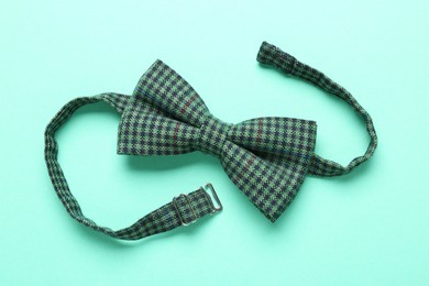 Photo of Stylish gingham bow tie on light green background, top view