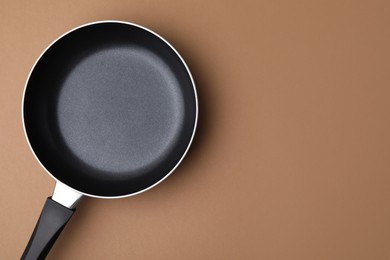 One frying pan on light brown background, top view. Space for text