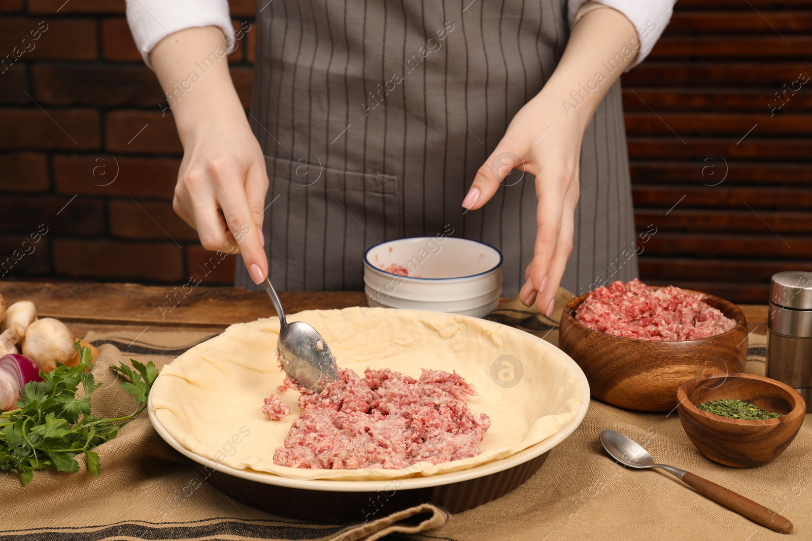 Photo of Woman making meat pie at wooden table, closeup