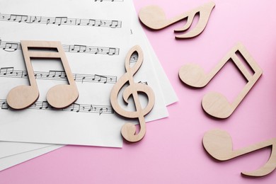 Photo of Baby songs. Music sheets and wooden notes on pink background, flat lay
