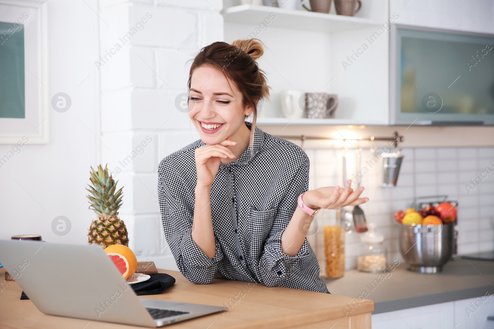 Photo of Young blogger with fruits and laptop on kitchen